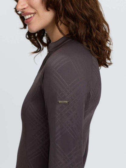LeMieux Heritage Check Long Sleeve Base Layer in Cocoa - Woman wearing equestrian top with logo.