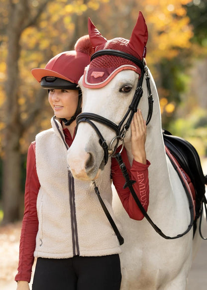 LeMieux equestrian young rider in red hat and cream gilet with white horse and matching red fly veil.