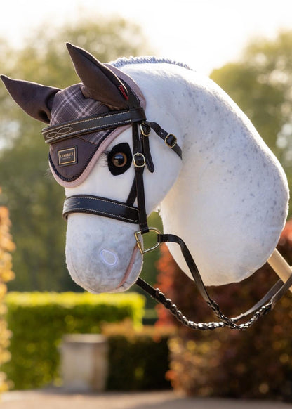 LeMieux hobby horse fly hood in heritage check print, with bridle, on a white spotted toy horse.