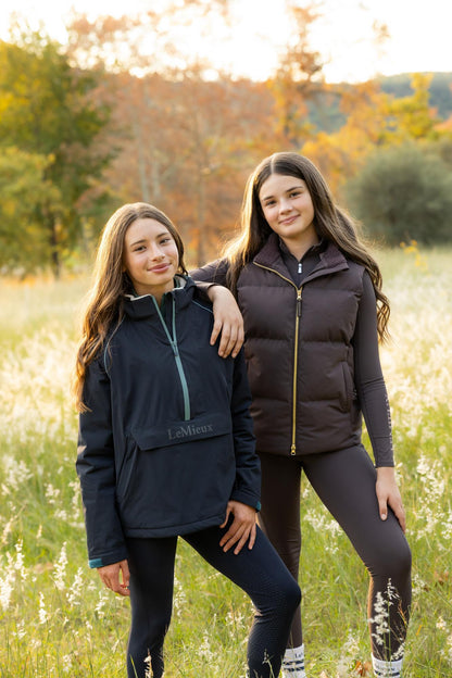 Young girl wearing LeMieux Bailey Waterproof Anorak in navy, outdoors in autumn.