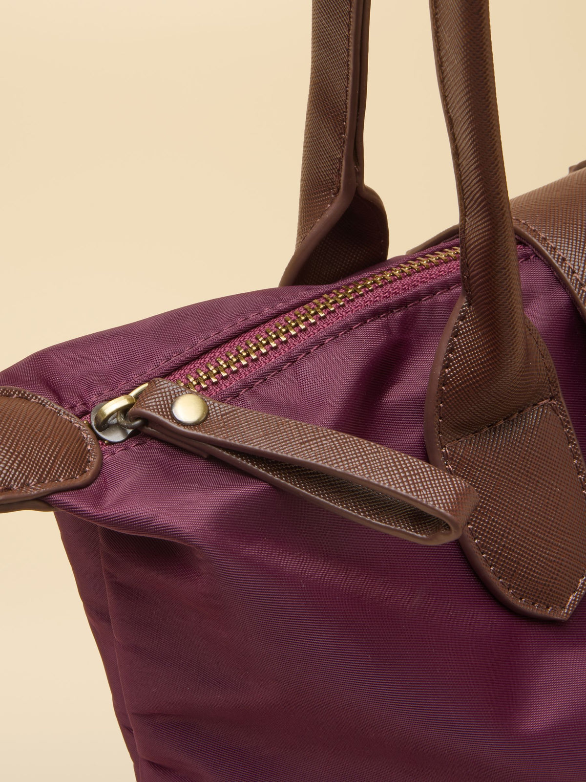 Burgundy nylon Joules shopper bag detail with brown leather trim and gold zipper.