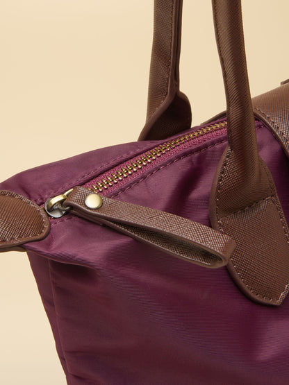 Burgundy nylon Joules shopper bag detail with brown leather trim and gold zipper.