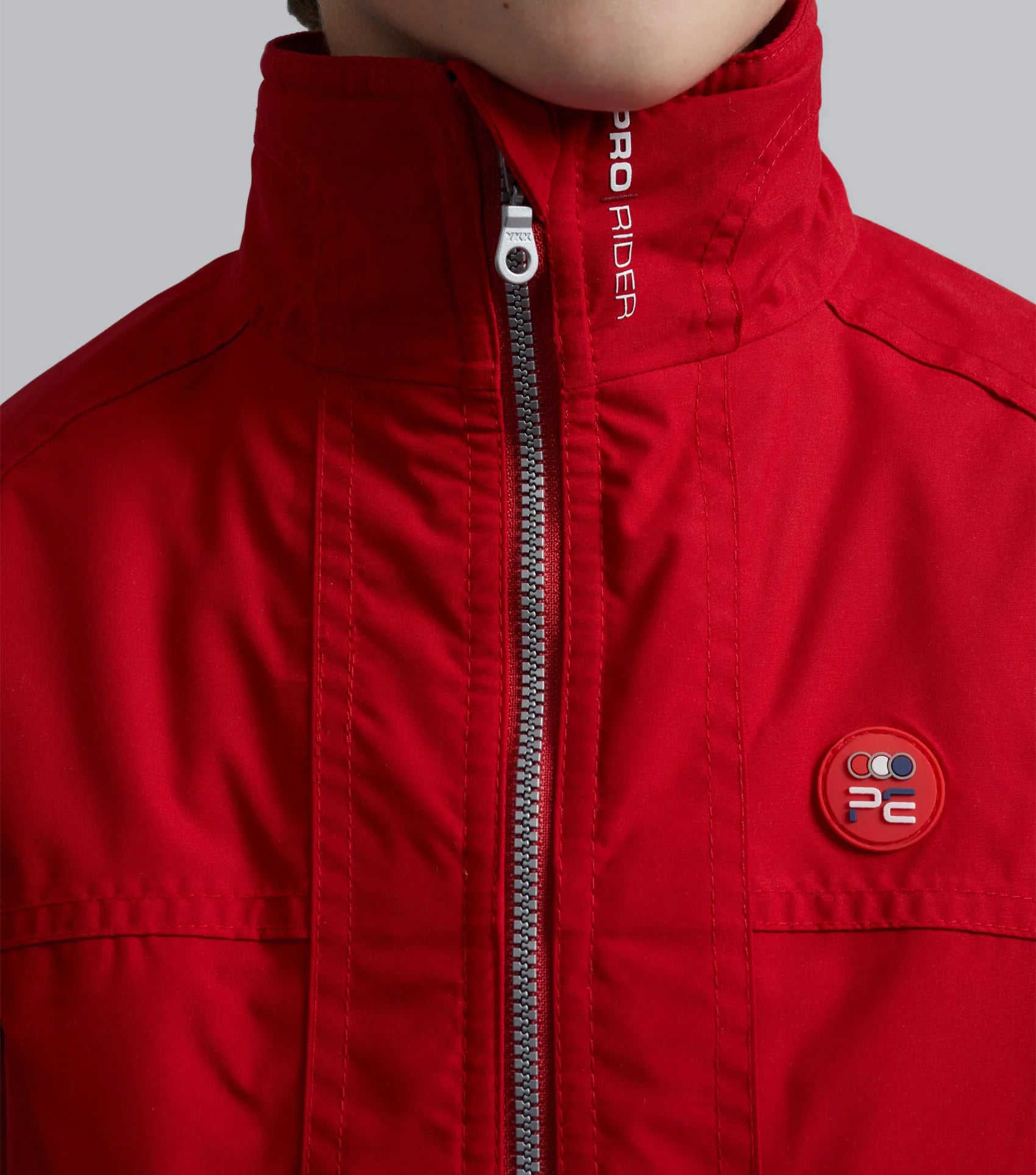 Red Junior Pro Rider Jacket by Premier Equine: Waterproof riding coat with zipper and logo detail.