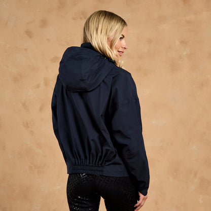 Woman in navy blue Toggi Meyer waterproof hooded blouson jacket, seen from the back and side profile.