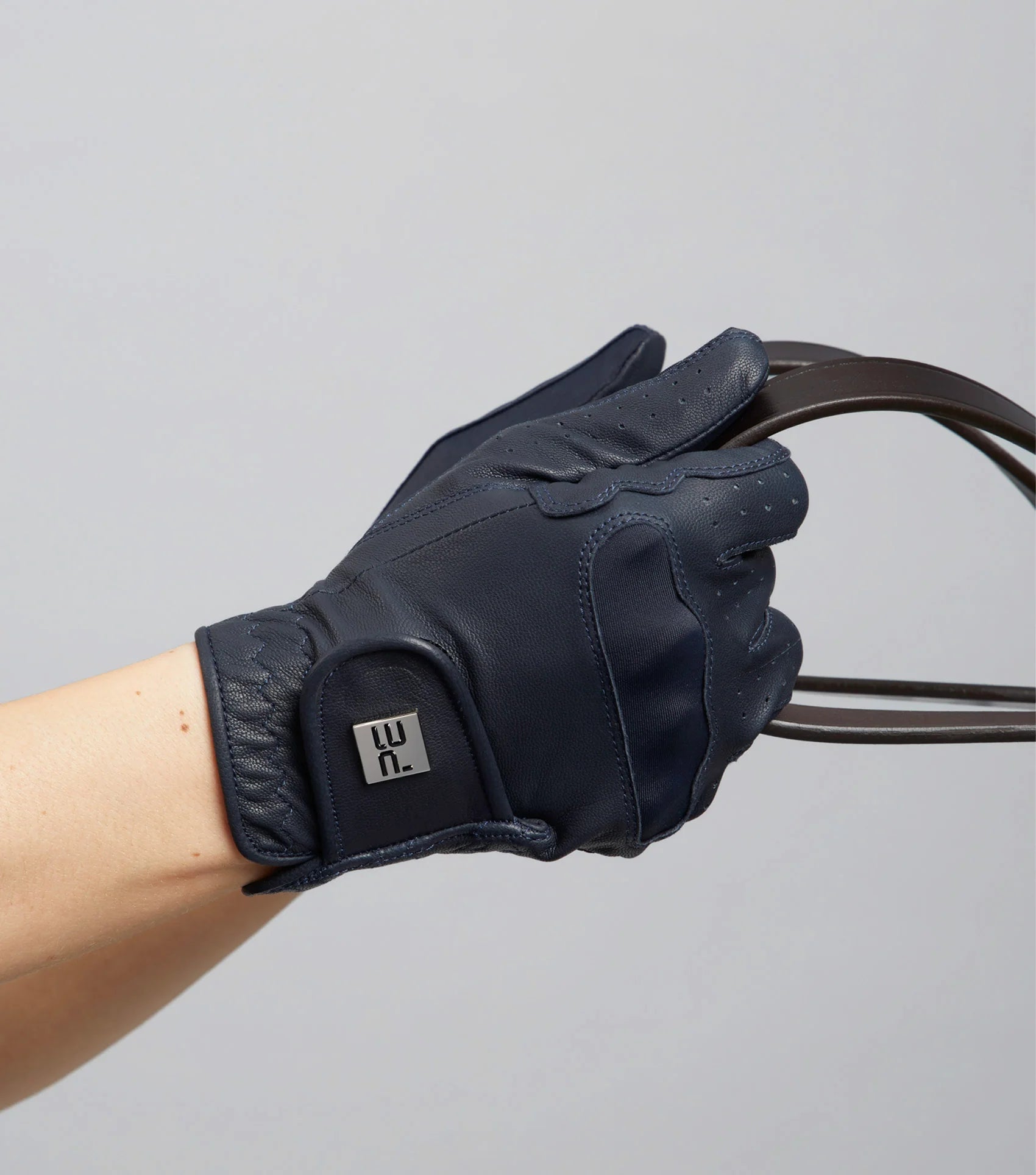 Navy Premier Equine leather riding glove on hand holding reins. Women's glove detail, Equiflair