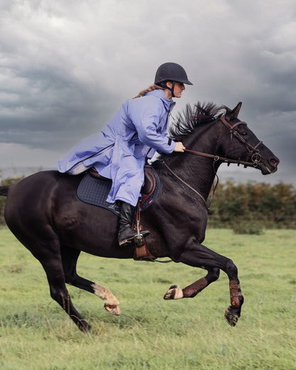 EQUIDRY women's long waterproof horse riding coat in blue lilac/grey showing rider galloping on horse