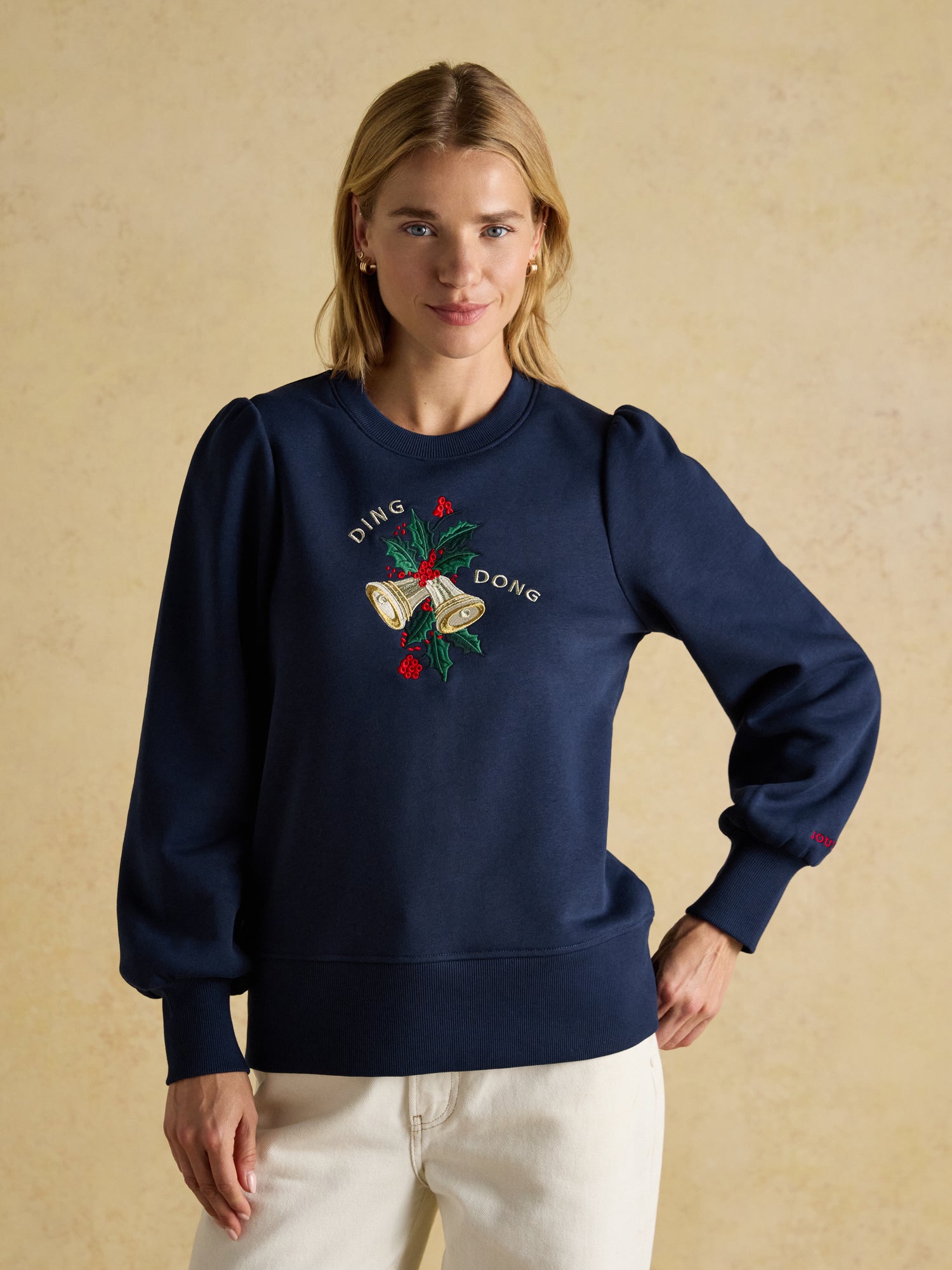 JOULES Robyn Navy Sweatshirt - Christmas Bells Embroidery, Long Puff Sleeves. Woman wearing navy holiday sweatshirt