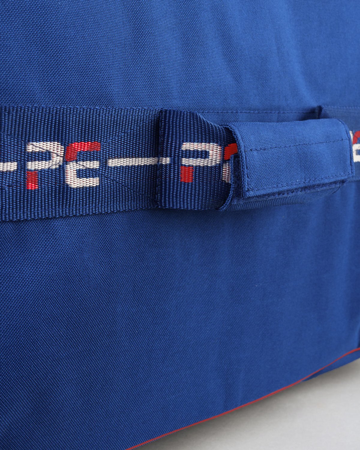 Premier Equine Navy Storage Bag Close-up: Durable equestrian gear bag with woven strap and logo detail.