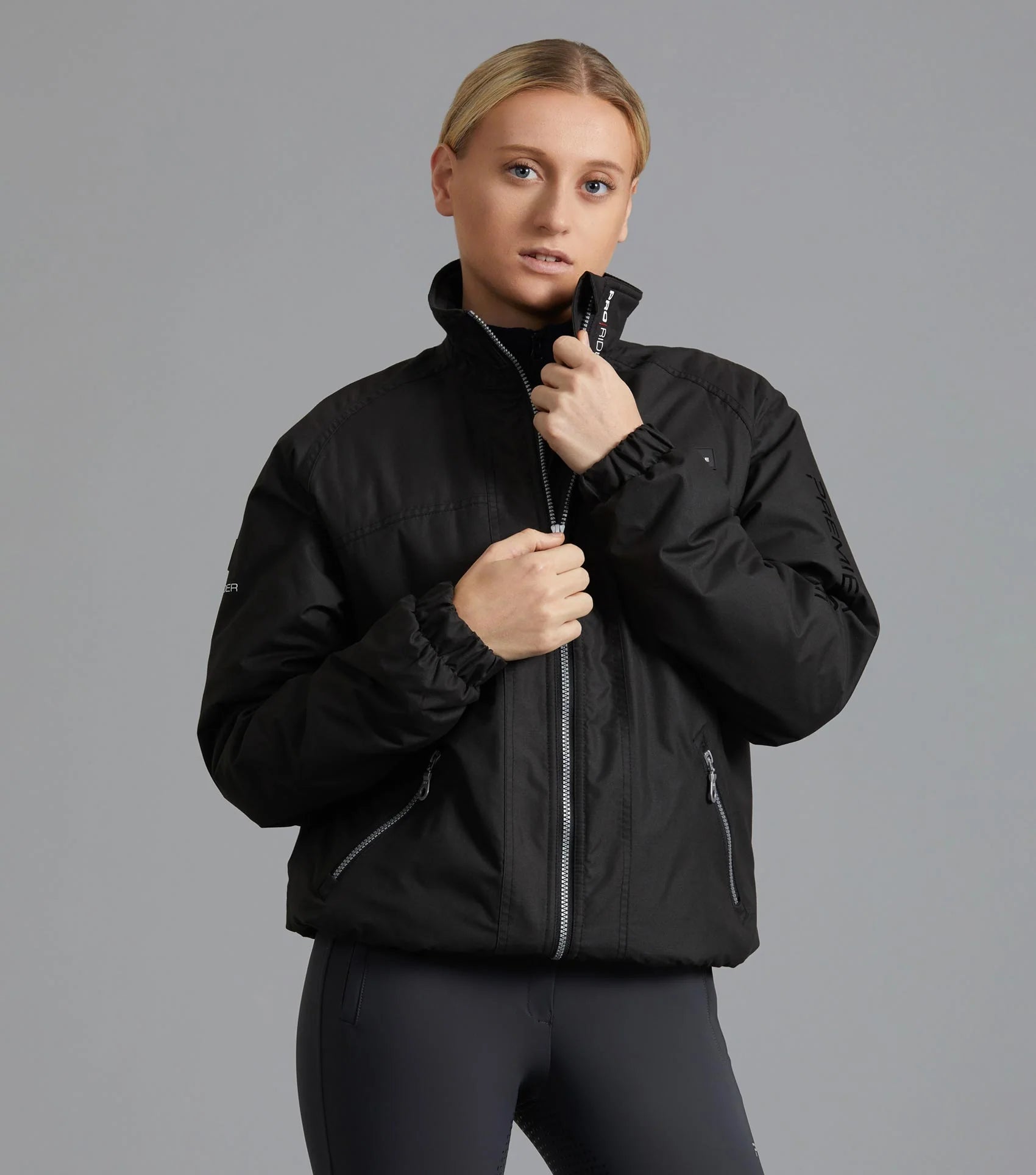 Woman wearing PREMIER EQUINE PRO RIDER Unisex Waterproof Riding Jacket Black - Equiflair riding coat