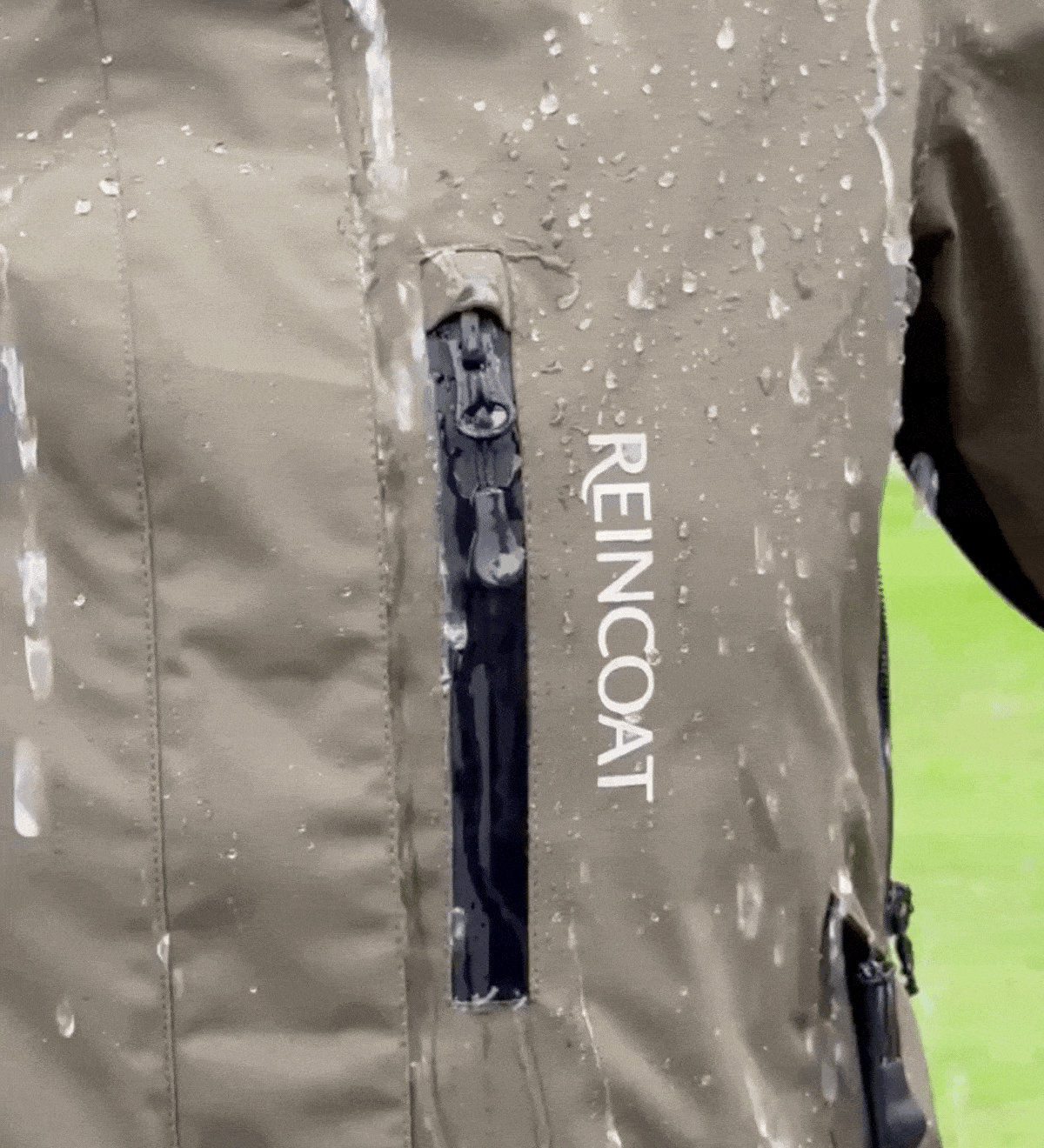 REINCOAT waterproof jacket - Olive. Close-up view of the brand on the waterproof jacket, showing water droplets.
