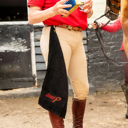 Equiflair Smart Grooming Handy Towel: Black cotton horse grooming towel with brass clip attached to rider's breeches.