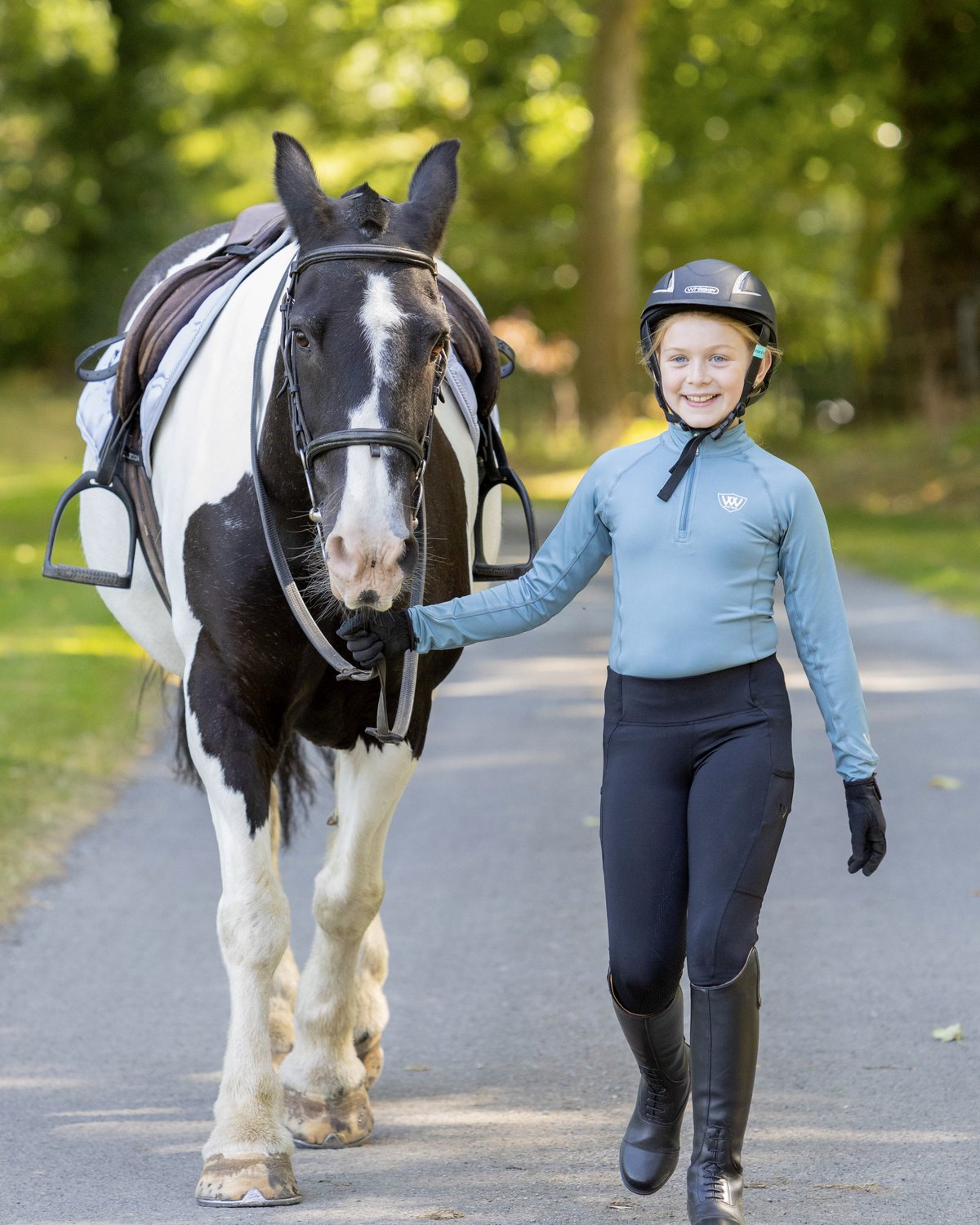 Woof Wear Young Rider Pro Tights in Black: A young rider with her horse, showcasing the comfortable fit & style of the riding tights.