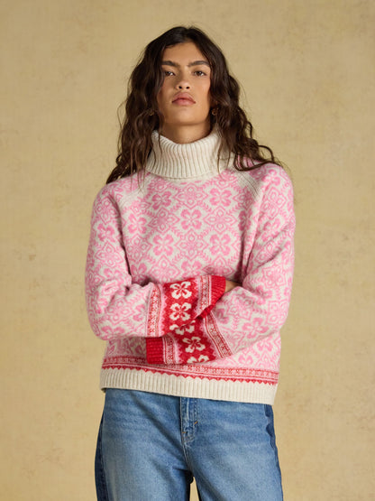 Women's Joules pink Nordic pattern knitted jumper with detachable roll neck and blue jeans.