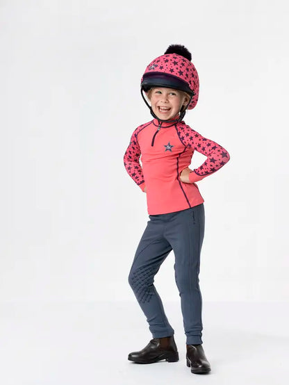 Girl Wearing Lemieux Mini Base Layer in Papaya. Equestrian Kids Fashion, Horse Riding Outfit, Lemieux Star Helmet