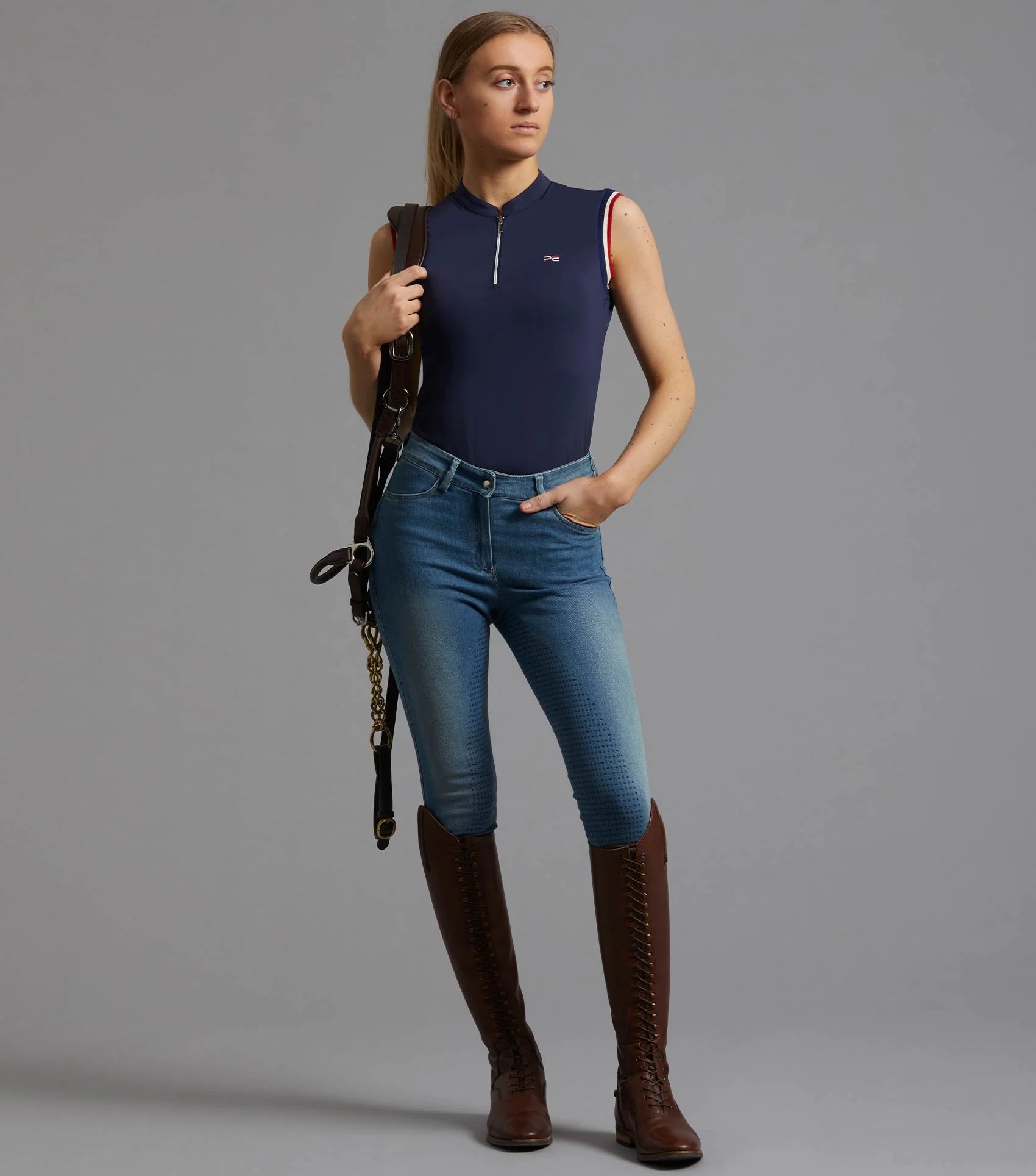 Premier Equine Alito Ladies Sleeveless Riding Top - Navy Equestrian Shirt with Brown Boots and Riding Crop