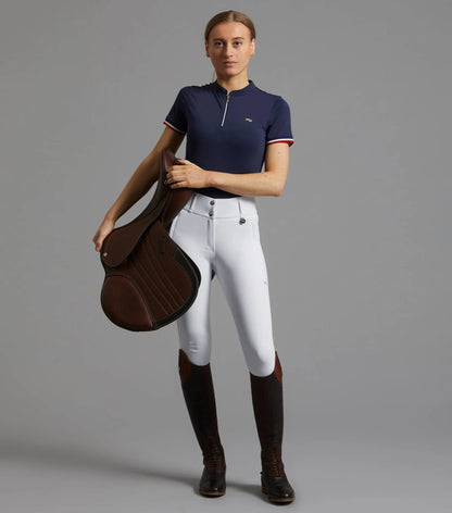 Equestrian: Woman in Premier Equine Navy Riding Top, White Breeches & Boots Holding Saddle