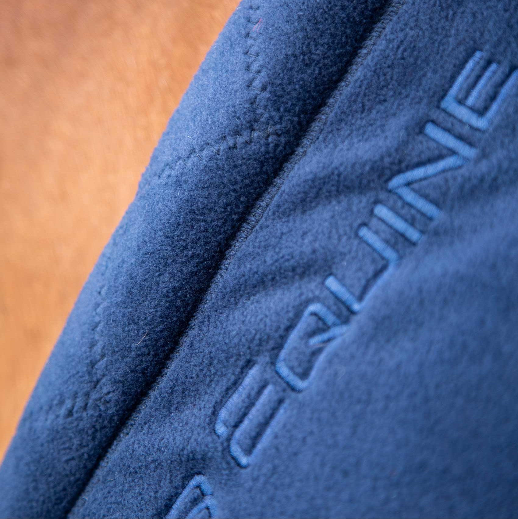 Premier Equine Buster Fleece Cooler Rug - Continental Edition Navy. Detail of embroidered logo on fleece.