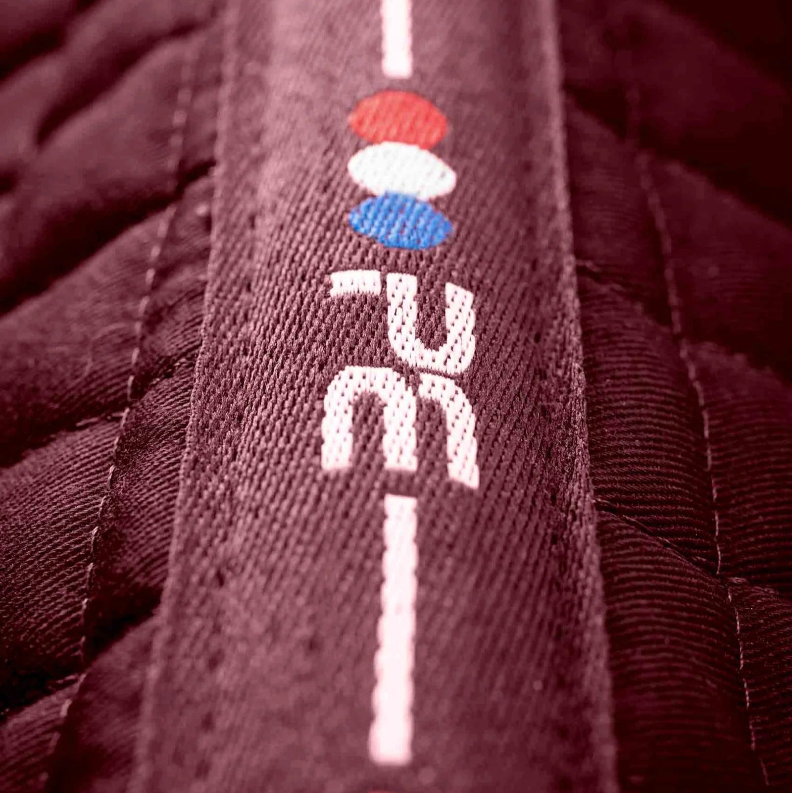 Premier Equine burgundy cotton cross country saddle pad close-up. Equestrian gear for eventing. High wither design, anti-rub protection.