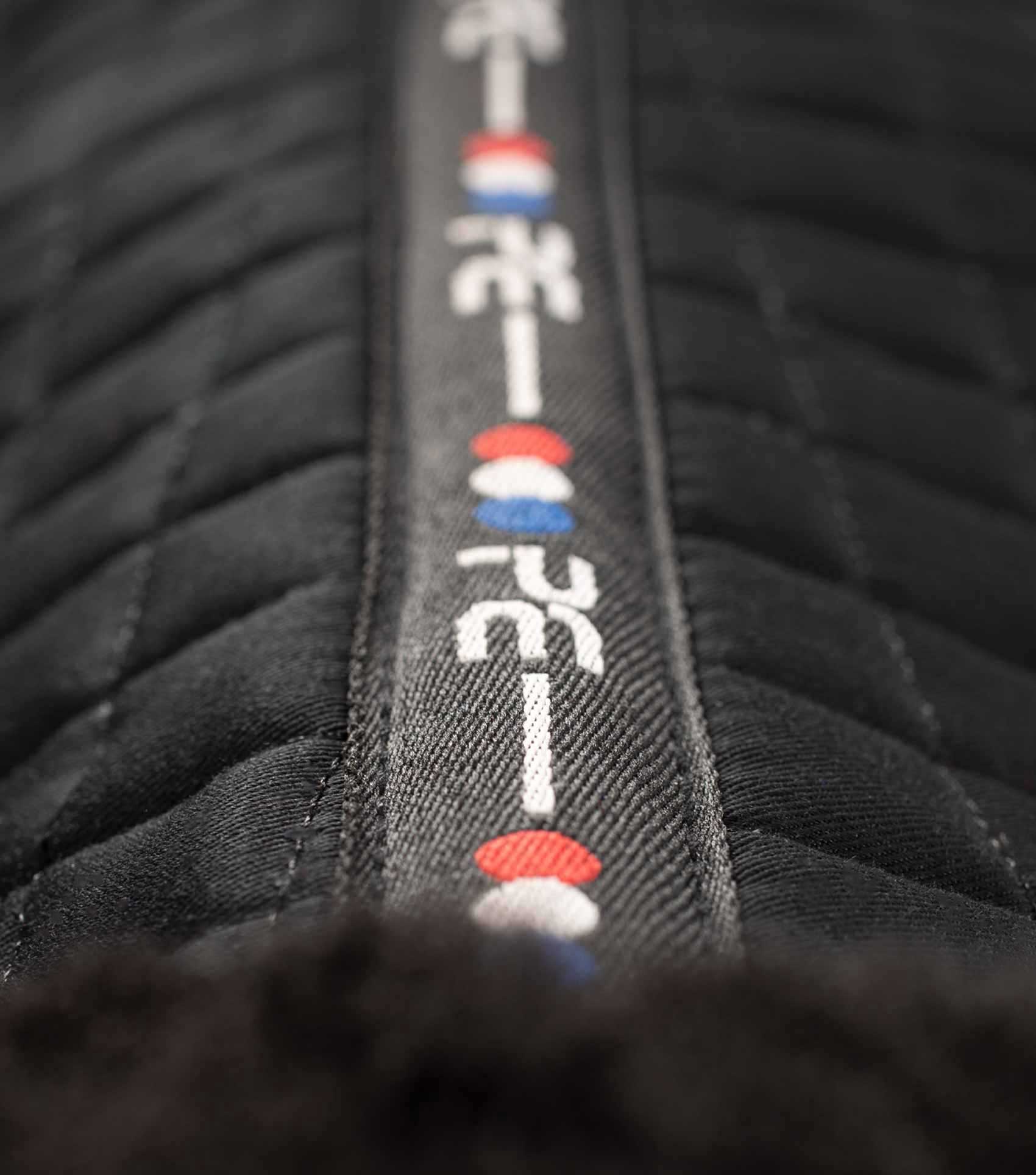 Premier Equine Merino Wool Saddle Pad - Black. Close-up showing stitching and red, white and blue logo detail.