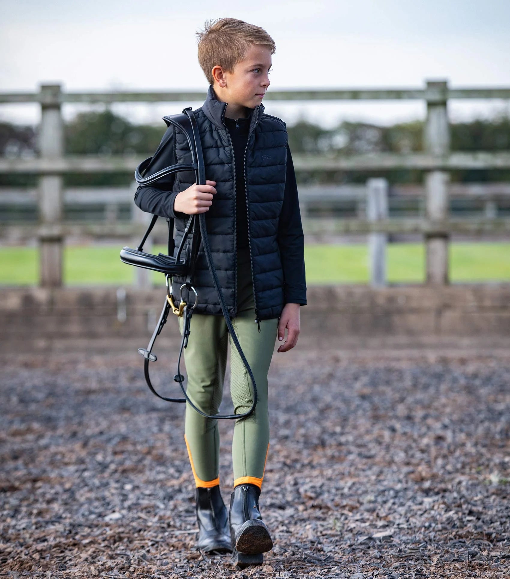 Young equestrian in black Premier Equine Dante Junior Riding Gilet and riding apparel.