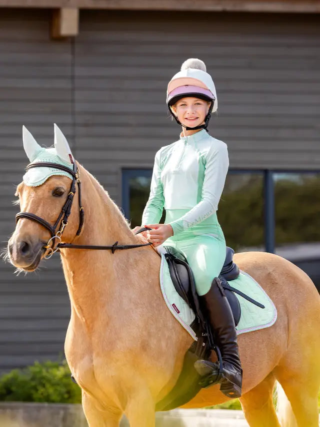 LeMieux Harlow Softmint Base Layer: Equestrian girl and palomino horse in matching attire. Equiflair store image.