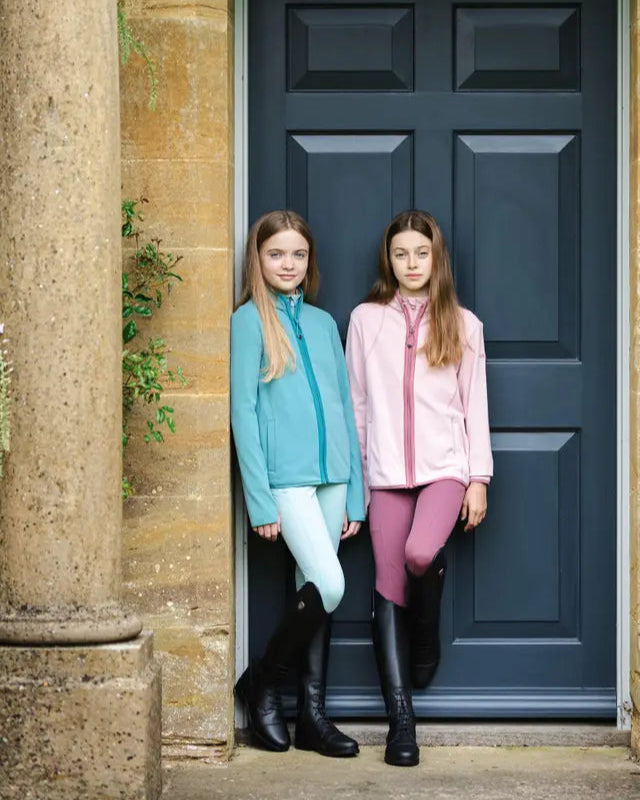 Two young girls in LeMieux Felicity Fleece Zip Through Lagoon and riding gear from Equiflair. Equine fashion, riding apparel