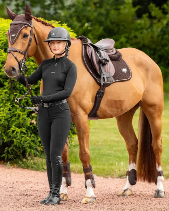 Chestnut horse with rider in black equestrian apparel & Lemieux Puissance brown saddle pad. English riding style.