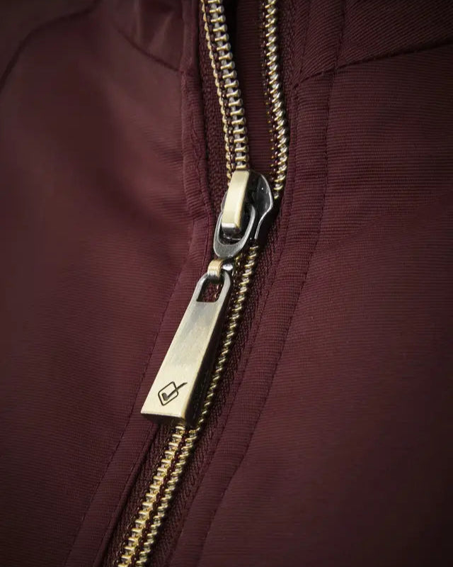 Lemieux Elite Crew Jacket Burgundy: Close-up of zipper detail, gold hardware, and logo. Waterproof & wind resistant.