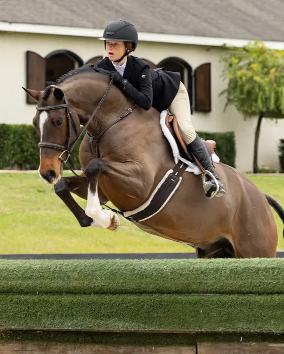 LeMieux Merino+ Hunter Saddle Pad in White: Horse and Rider Jumping over obstacle.