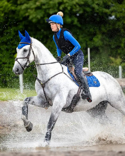 Equestrian Action: Horse Riding a Grey Horse Through Water. LeMieux Loire Close Contact Saddle Pad. Water Splash