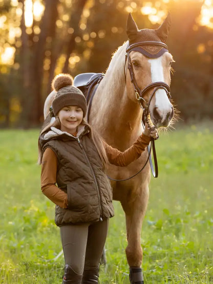 Girl with palomino horse wearing a LeMieux beanie. Equestrian lifestyle.