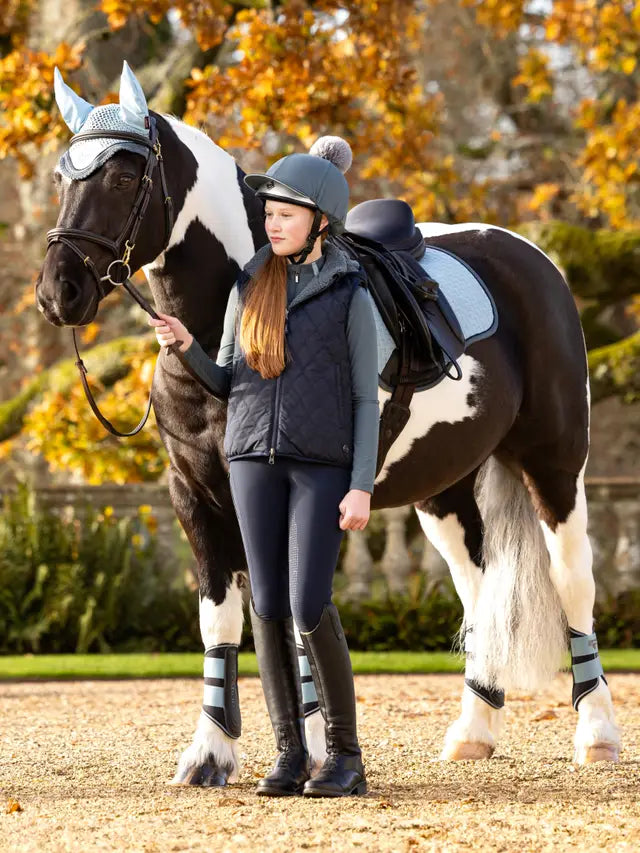 Girl with black and white horse wearing LEMIEUX Petrol Pom Hat Silk. Equestrian apparel, horse riding equipment. Equiflair.