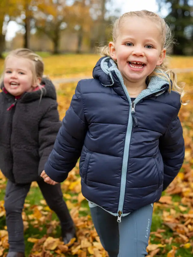 Two happy girls in Lemieux puffer jackets outdoors. Children's equestrian style, water resistant winter coats.