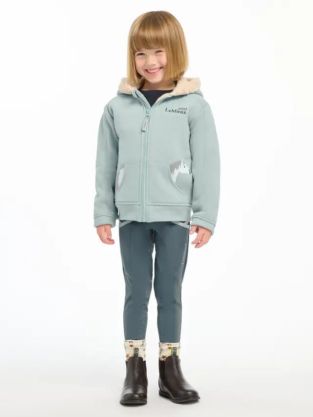 LEMIEUX MINI CHARLIE LINED HOODIE GLACIER on child. Kids equestrian apparel from Equiflair. Zip-up cozy hoodie with pony details.