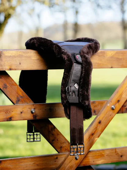 LeMieux Merino+ Anatomic Long Stud Girth Cover Brown hanging on fence