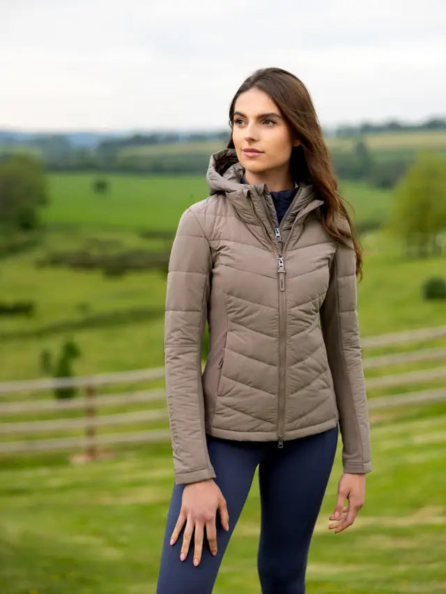 Woman wearing a Lemieux Brioney Hybrid Jacket in Pecan outdoors. Hooded jacket, women's fashion, equestrian style.