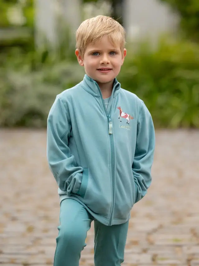 Boy in LeMieux Mini Mari Micro Fleece Aqua. Children's Equestrian Clothing. Cozy fleece jacket for kids.