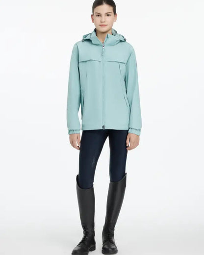 LeMieux Young Rider Dolcie Waterproof Jacket - Aqua. Girl in riding boots wearing a waterproof jacket.