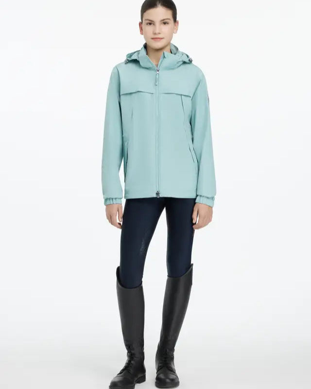 LeMieux Young Rider Dolcie Waterproof Jacket - Aqua. Girl in riding boots wearing a waterproof jacket.