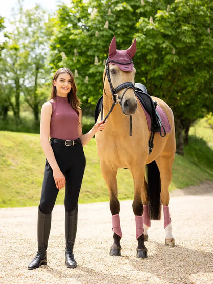 Equestrian girl with horse wearing LeMieux Rosewood sleeveless top, black riding pants & boots. Horse in Rosewood fly bonnet and leg wraps