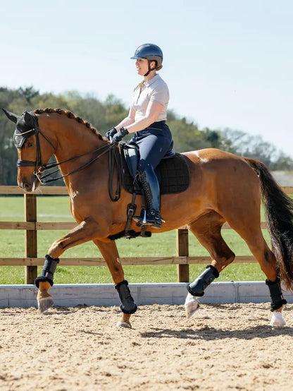 Equestrian Performance: Woman riding horse with LeMieux 3D Mesh Dressage Square Cooling Pad in Black. Optimal Temperature Control