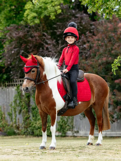 Child riding pony with red LeMieux Mini Suede Close Contact Square Chilli saddle pad. Equestrian style for kids and ponies.