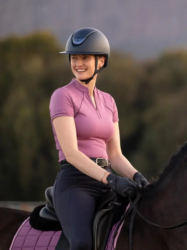 Woman equestrian rider wearing LeMieux Mallow mesh base layer, horse riding