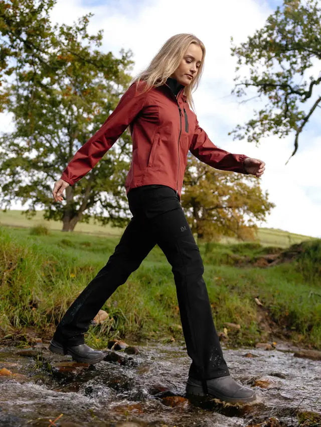 Woman wearing Lemieux Stormwear waterproof equestrian trousers in black, walking through a stream.