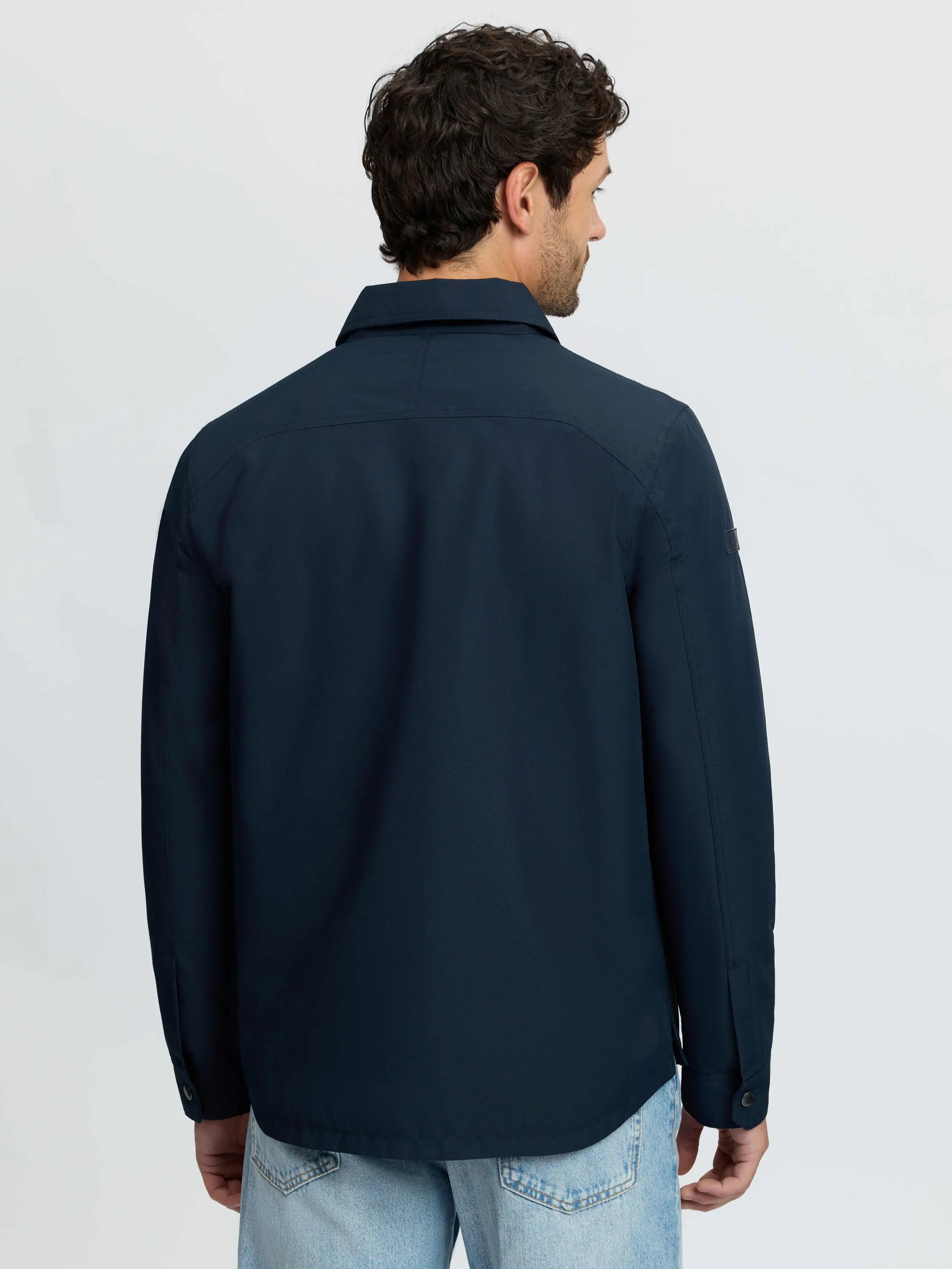 Back view of a man wearing a navy blue LEMIEUX water-resistant insulated shacket with taped seams and quilted lining.
