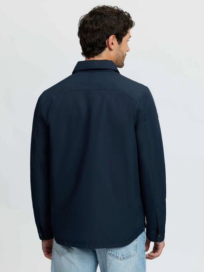 Back view of a man wearing a navy blue LEMIEUX water-resistant insulated shacket with taped seams and quilted lining.