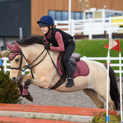 Child equestrian rider in Charles Owen Kontor body protector jumping horse. Equestrian safety wear. Horse jumping, riding equipment.