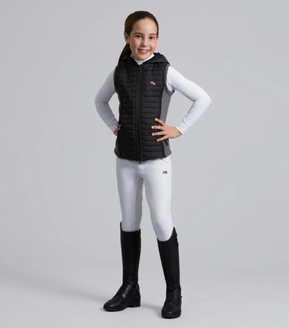 Girl in Premier Equine Black Hybrid Riding Gilet. Equestrian style with riding boots and white breeches.