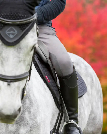 Equestrian: Grey horse with Lemieux EuroJump Square Black saddle pad & black riding boots. Horseback riding gear.
