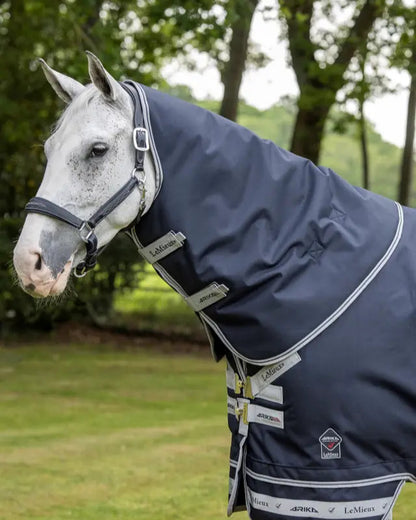 Grey horse wearing a navy LEMIEUX ARIKA Storm-Tek 100g Neck Cover for equine protection. Waterproof horse neck warmer.